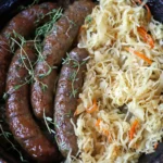 German-style bratwurst served with sauerkraut on a rustic plate, traditional sausage recipe with mustard and herbs