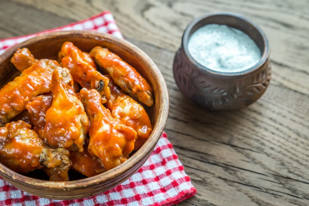 Crispy oven-baked Buffalo wings coated in spicy buffalo sauce served on a plate with celery sticks and dipping sauce
