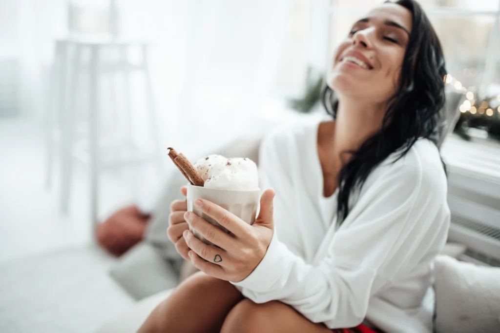 Festive Coquito in a glass with cinnamon stick and grated nutmeg, traditional Puerto Rican Christmas drink on a holiday table.