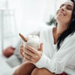 Festive Coquito in a glass with cinnamon stick and grated nutmeg, traditional Puerto Rican Christmas drink on a holiday table.