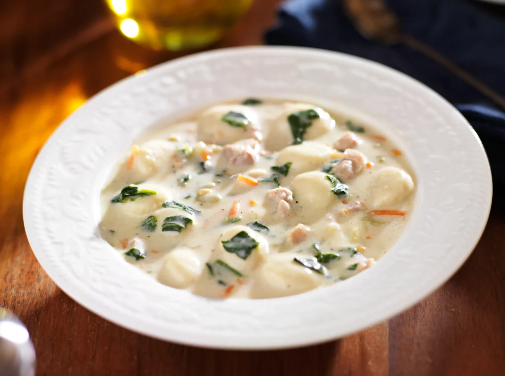 Creamy one-pot chicken gnocchi soup with spinach and carrots in a rustic bowl