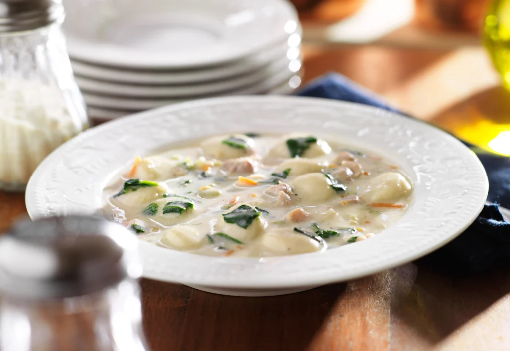 Creamy one-pot chicken gnocchi soup with spinach and carrots in a rustic bowl