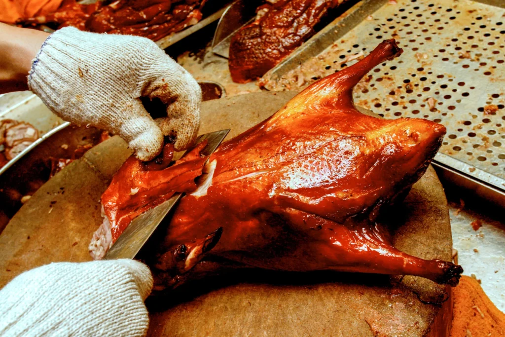 Traditional Peking Duck recipe served with hoisin sauce, thin pancakes, and fresh scallions on a wooden platter