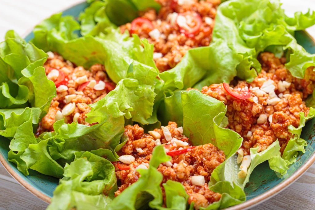 Delicious Asian-style lettuce wraps filled with savory chicken, vegetables, and hoisin sauce on a white plate