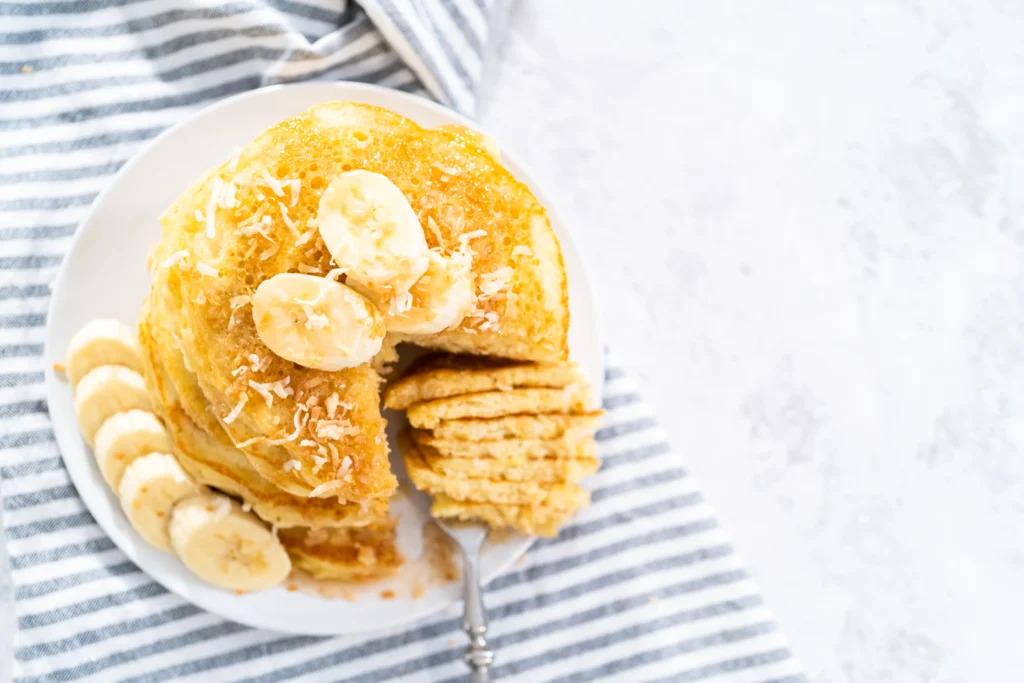 Stack of healthy protein pancakes with oats and banana topped with fresh berries and honey