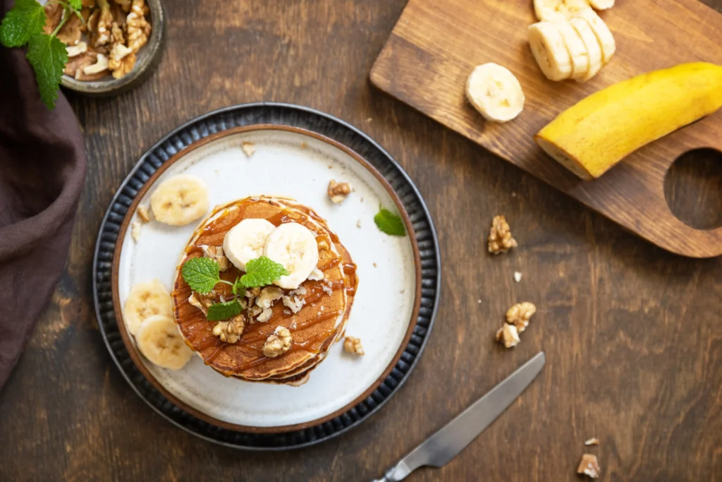 Stack of healthy protein pancakes with oats and banana topped with fresh berries and honey