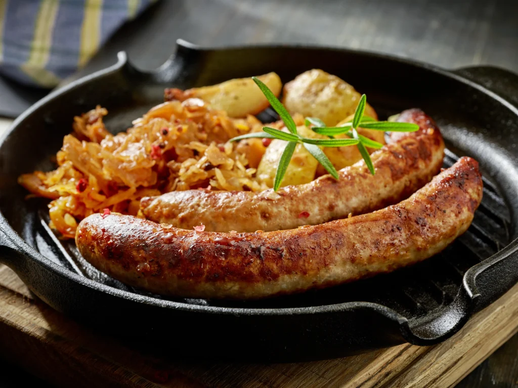 German-style bratwurst served with sauerkraut on a rustic plate, traditional sausage recipe with mustard and herbs