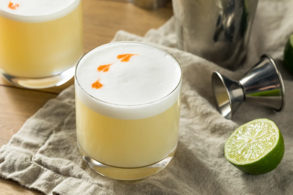 Perfect Pisco Sour cocktail in a chilled glass topped with creamy foam and fresh lime garnish