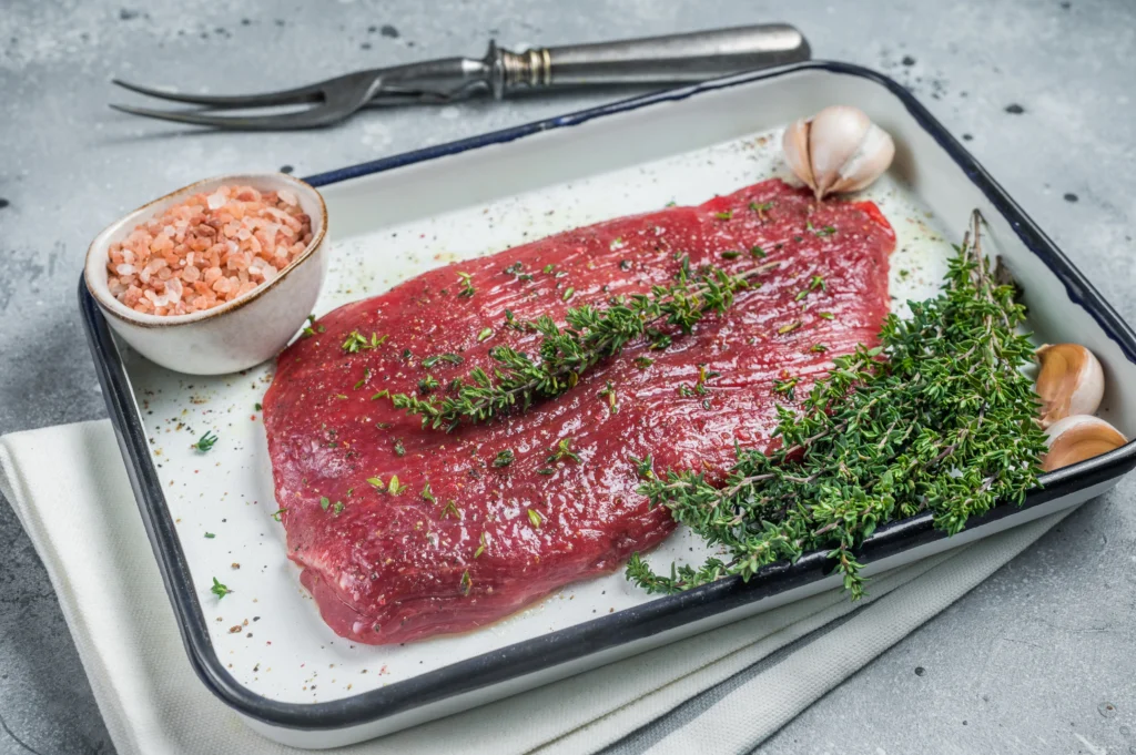 Quick London Broil recipe with garlic and herbs served on a wooden cutting board, juicy and perfectly cooked