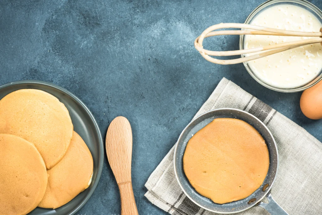 Stack of fluffy classic Bisquick pancakes topped with butter and maple syrup on a breakfast plate