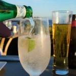 Refreshing Hugo Spritz cocktail with prosecco, elderflower syrup, lime slices, mint leaves, and ice in a wine glass