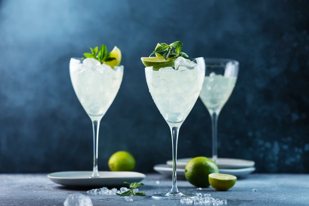 Refreshing Hugo Spritz cocktail with prosecco, elderflower syrup, lime slices, mint leaves, and ice in a wine glass
