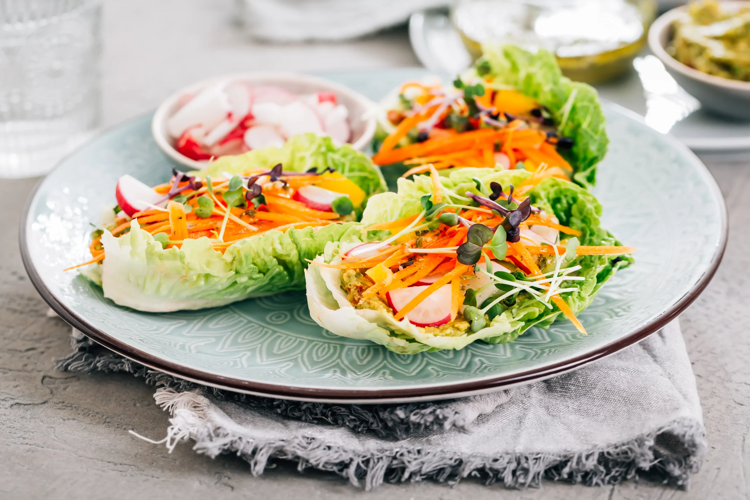 Fresh vegetarian lettuce wraps filled with colorful vegetables and tofu, served in crisp green lettuce leaves