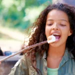 Soft, fluffy homemade marshmallows dusted with powdered sugar, cut into cubes and served on a rustic wooden board.