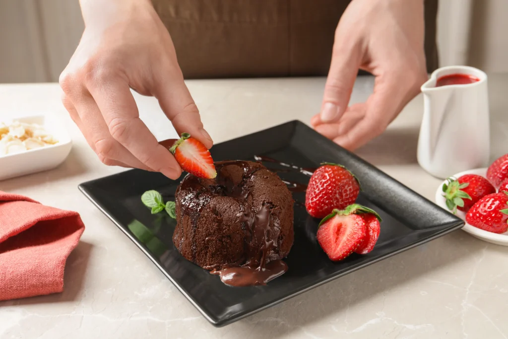 Romantic lava cake with molten chocolate center served on a plate with strawberries and ice cream for a date night dessert