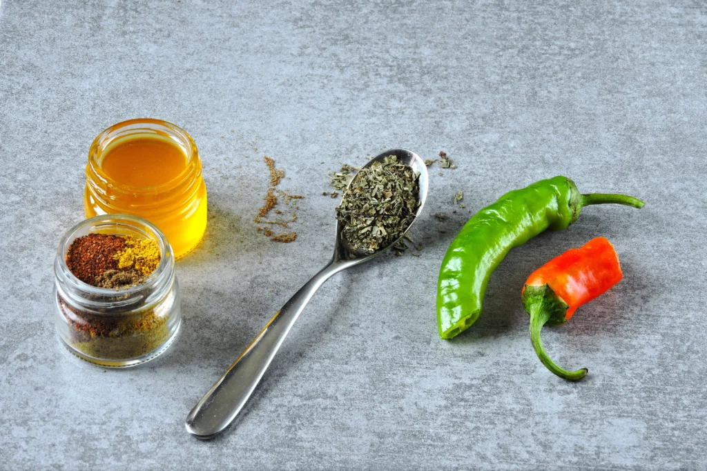 Jar of homemade spicy hot honey being drizzled over crispy fried chicken on a wooden table