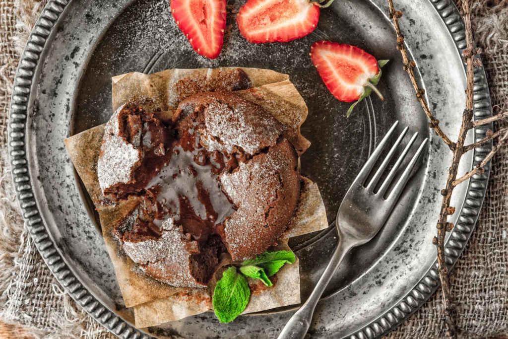Romantic lava cake with molten chocolate center served on a plate with strawberries and ice cream for a date night dessert