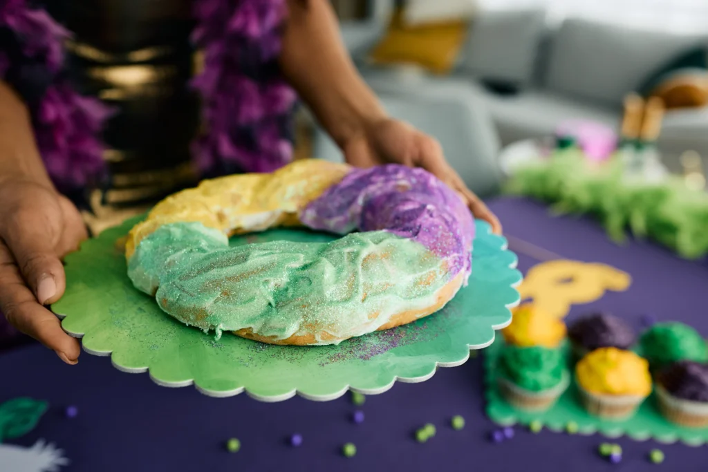 King Cake Recipe
Homemade King Cake decorated with purple, green, and gold sugar icing, sliced to reveal soft cinnamon filling inside on a festive table
