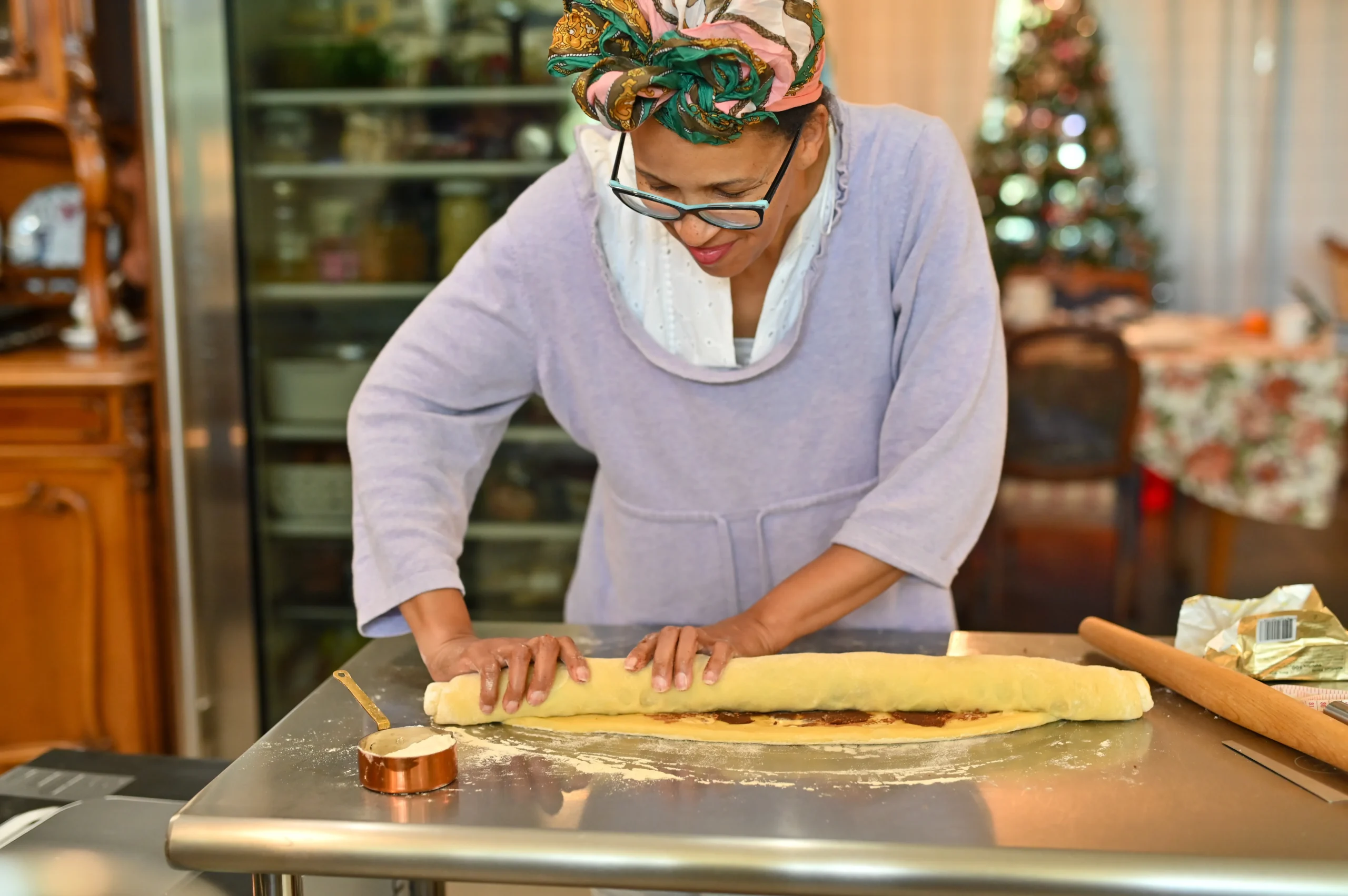 Homemade King Cake decorated with purple, green, and gold sugar icing, sliced to reveal soft cinnamon filling inside on a festive table