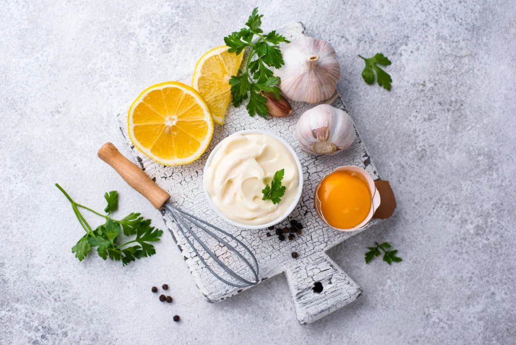 Vegan Garlic Aioli RecipeVegan garlic aioli in a small bowl, creamy and smooth, served with fresh herbs and dipping vegetables, egg-free and dairy-free sauce.