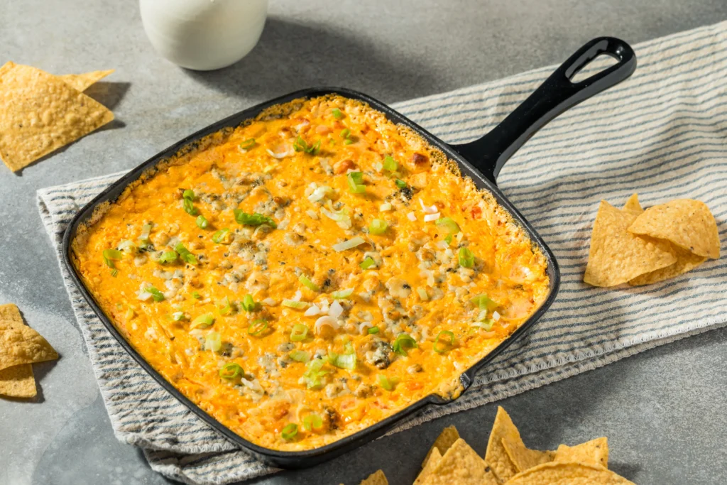 A bowl of creamy Rotel dip made with melted cheese, ground beef, and tomatoes with chilies, served with tortilla chips for game day