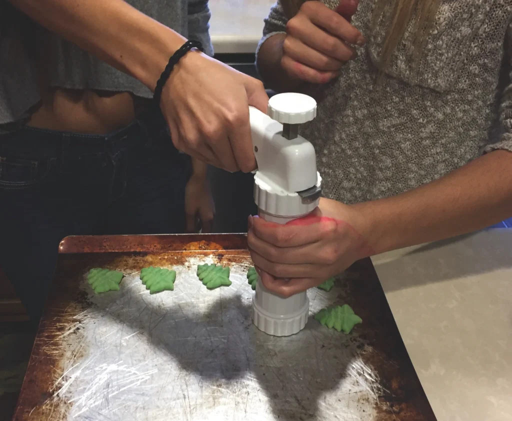 Buttery homemade spritz cookies in festive shapes on a baking tray, freshly baked and golden edges