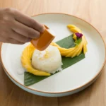Mango sticky rice served with coconut milk and fresh sliced mango on a plate