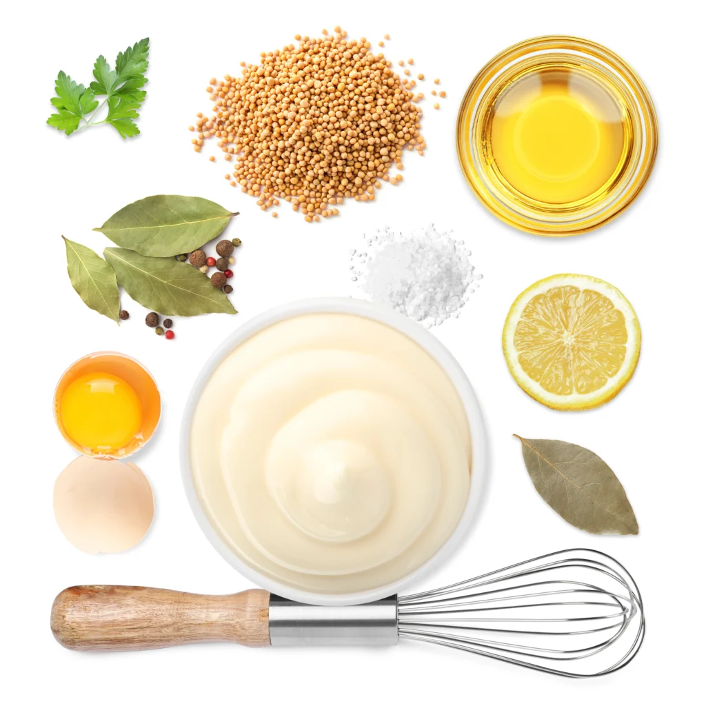 Creamy homemade Caesar dressing in a bowl with fresh salad ingredients on a wooden table