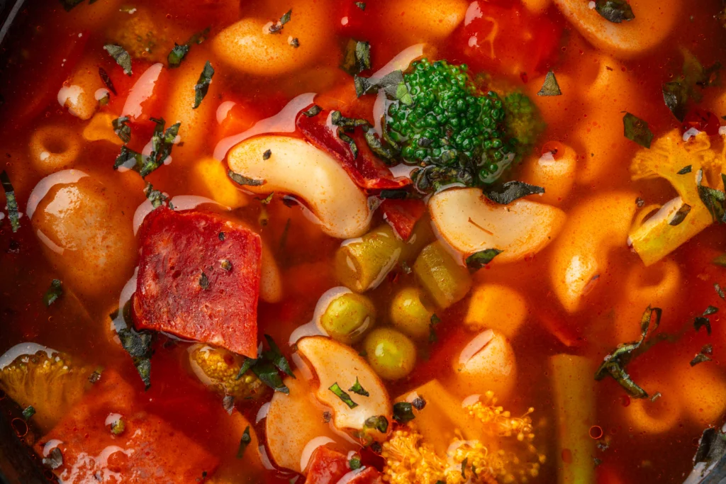 Hearty vegetable minestrone soup with beans, pasta, and fresh herbs in a rustic bowl