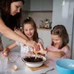 A fun dirt pudding dessert served in clear cups, layered with creamy chocolate pudding, crushed chocolate cookies, and gummy worms on top.