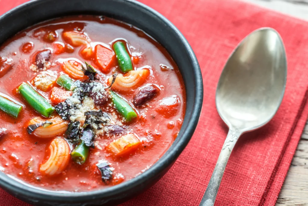 Hearty vegetable minestrone soup with beans, pasta, and fresh herbs in a rustic bowl