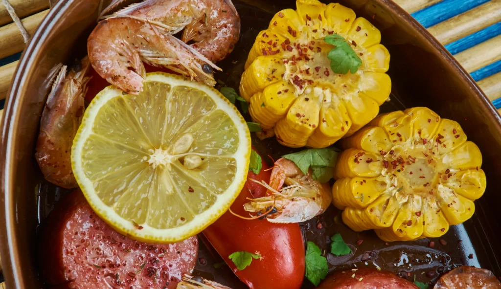 Cajun seafood boil with shrimp, crab legs, corn on the cob, potatoes, and spicy seasoning served on a rustic table