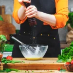 Vegan garlic aioli in a small bowl, creamy and smooth, served with fresh herbs and dipping vegetables, egg-free and dairy-free sauce.