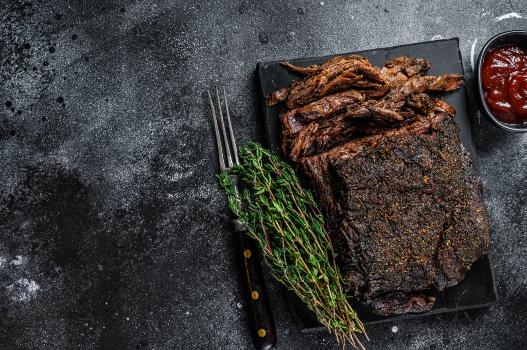 Smoked brisket sliced on a wooden board with a crispy bark and juicy interior, served at a BBQ party
