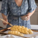 Freshly baked traditional challah bread with a golden braided crust on a wooden table for Shabbat dinner