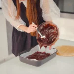 Freshly baked Texas Sheet Cake topped with rich chocolate frosting and chopped pecans on a rustic kitchen table
