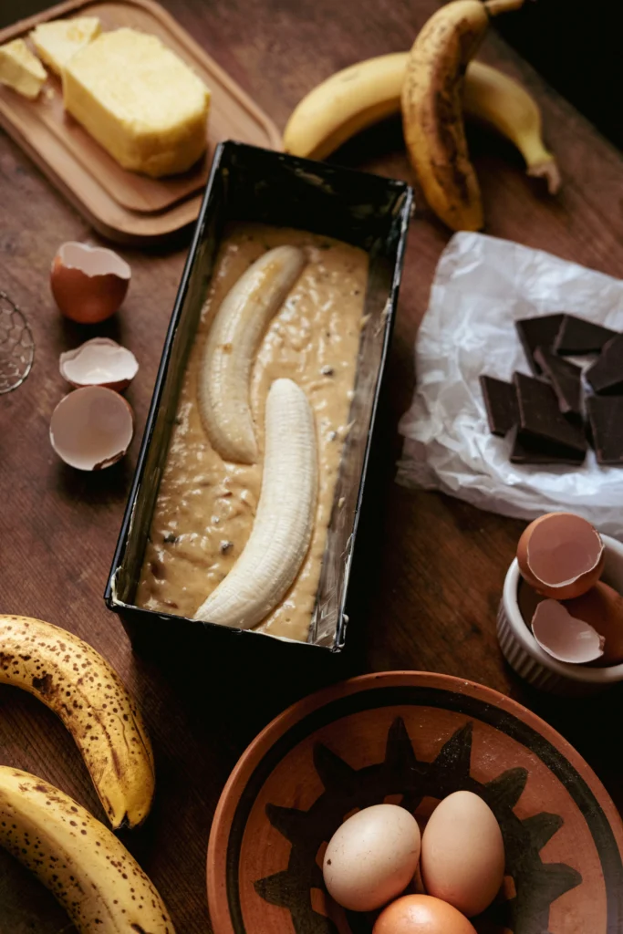 Freshly baked chocolate chip banana bread sliced on a wooden board, filled with melted chocolate chips and made with ripe bananas, perfect for beginner bakers.