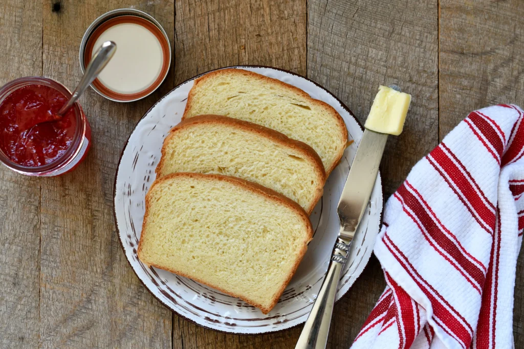 Freshly baked fluffy white sandwich bread sliced on a wooden board, showing a soft and airy texture.