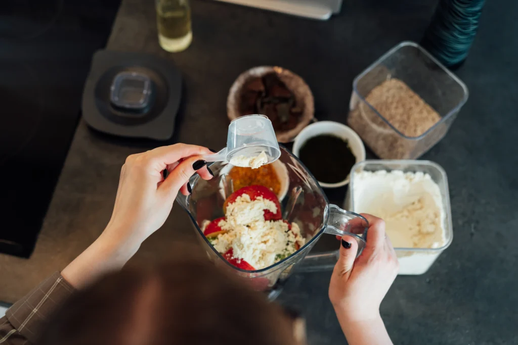 Glass of healthy protein shake made with banana, milk, and peanut butter on a kitchen counter