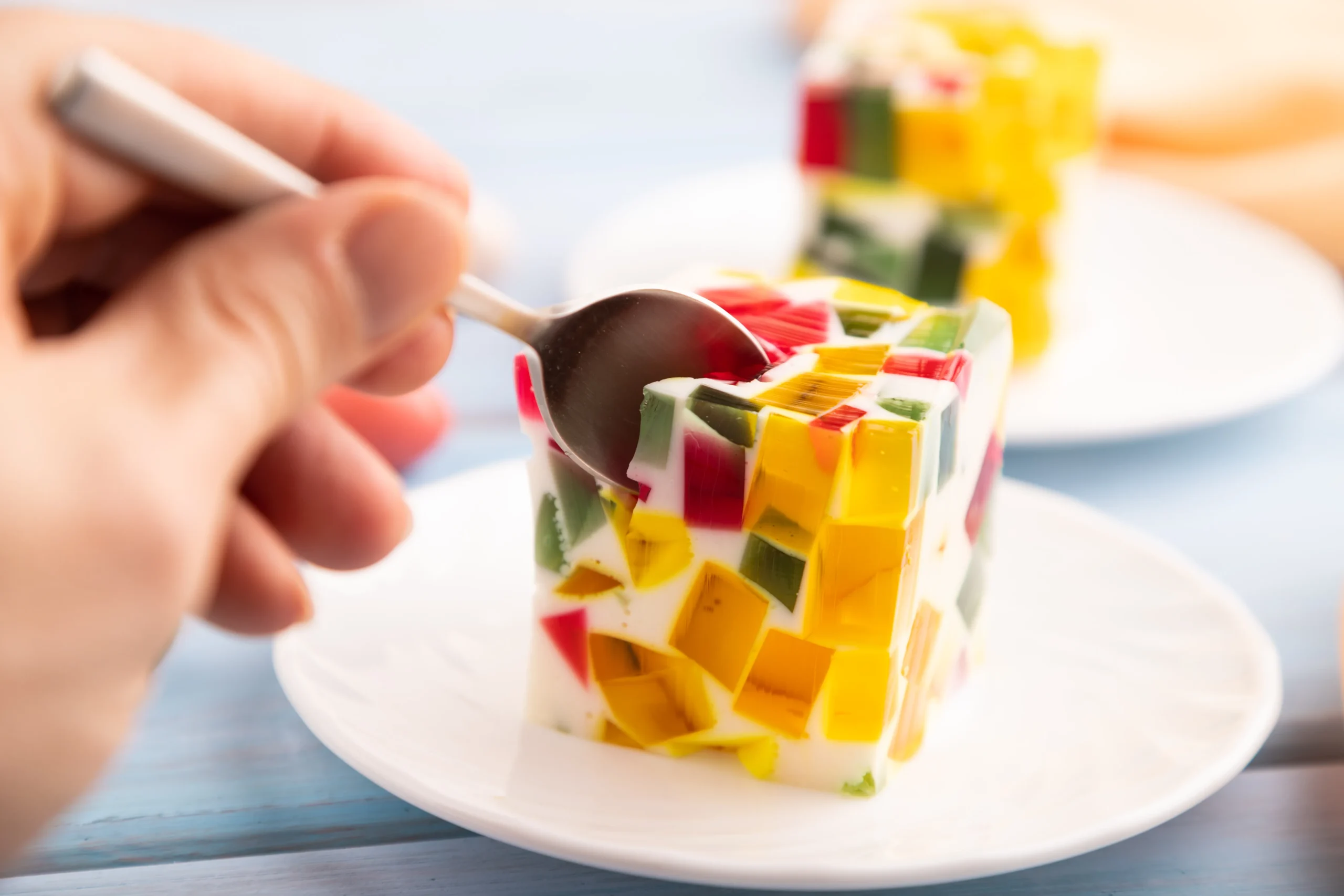 Colorful fruity gelatin dessert topped with fresh strawberries, kiwi, blueberries, and whipped cream in a glass serving dish.