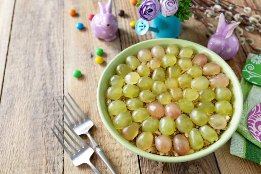 Creamy homemade grape salad with red and green grapes, topped with brown sugar and chopped pecans in a bowl