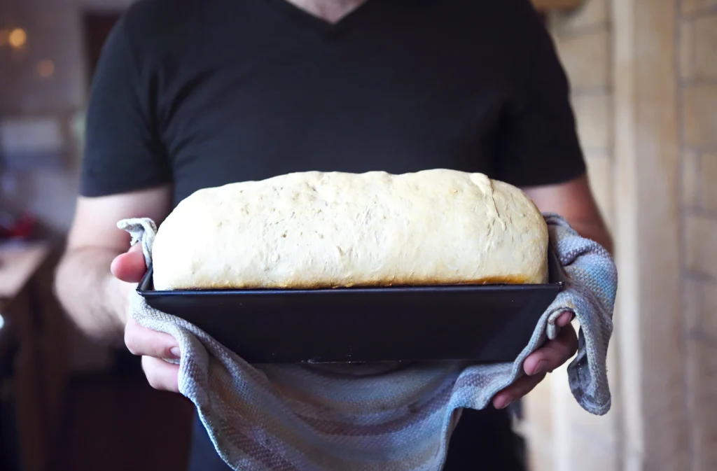 Freshly baked fluffy white sandwich bread sliced on a wooden board, showing a soft and airy texture.