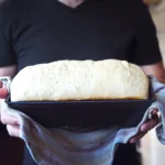 Freshly baked fluffy white sandwich bread sliced on a wooden board, showing a soft and airy texture.