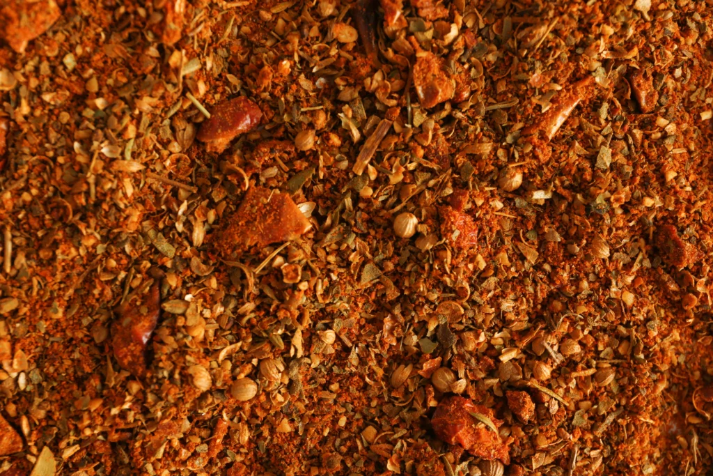 Homemade Tex-Mex fajita seasoning in a rustic bowl surrounded by colorful spices, peppers, and sizzling chicken fajitas