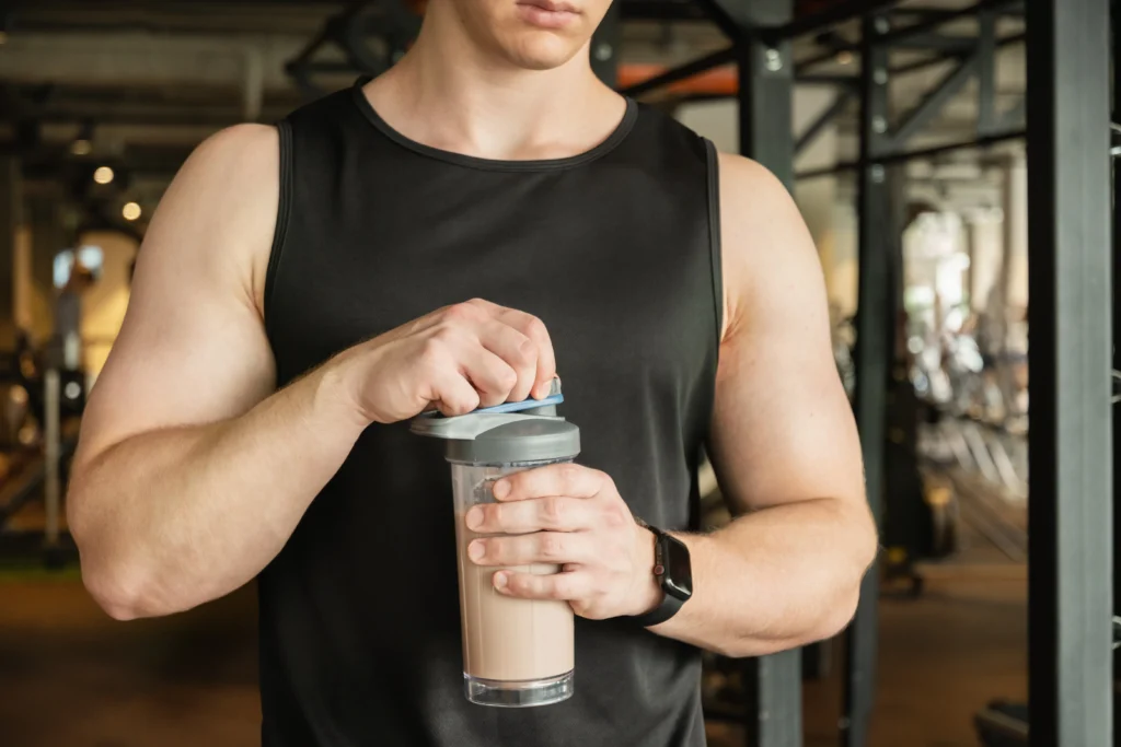 Glass of healthy protein shake made with banana, milk, and peanut butter on a kitchen counter