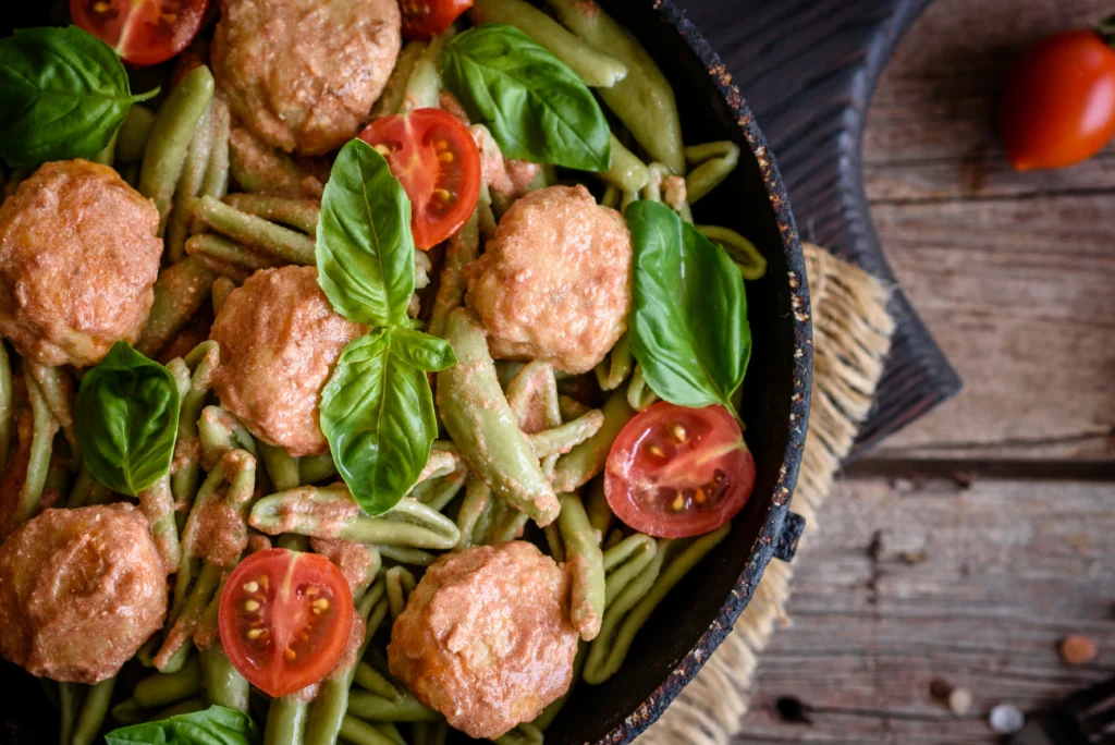 Turkey meatballs simmering in rich tomato sauce in a skillet, served with fresh herbs on top.