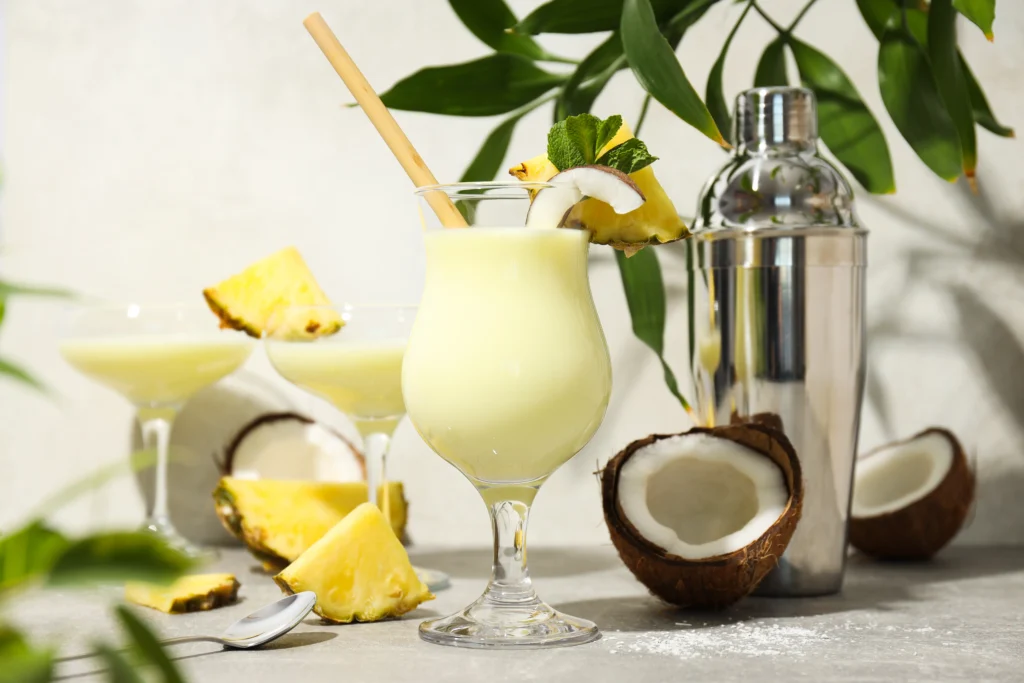 Creamy tropical pina colada cocktail served in a chilled glass with pineapple slices, coconut flakes, and cherries on a summer beach-themed table