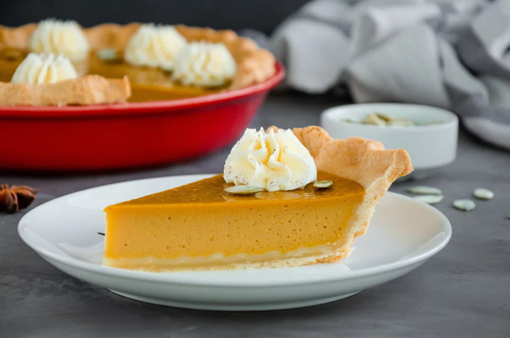 Classic Libby’s pumpkin pie topped with whipped cream on a wooden table during the holiday season
