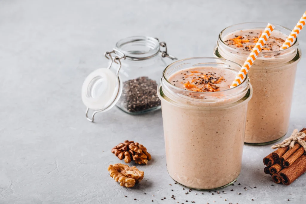 Glass of healthy protein shake made with banana, milk, and peanut butter on a kitchen counter