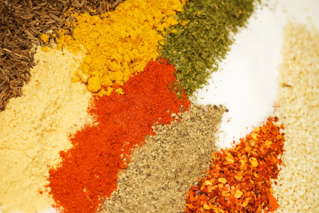 Homemade Tex-Mex fajita seasoning in a rustic bowl surrounded by colorful spices, peppers, and sizzling chicken fajitas